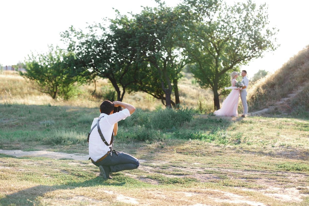 wedding photographer takes pictures of bride and groom in nature. wedding couple on photo shoot. photographer in action